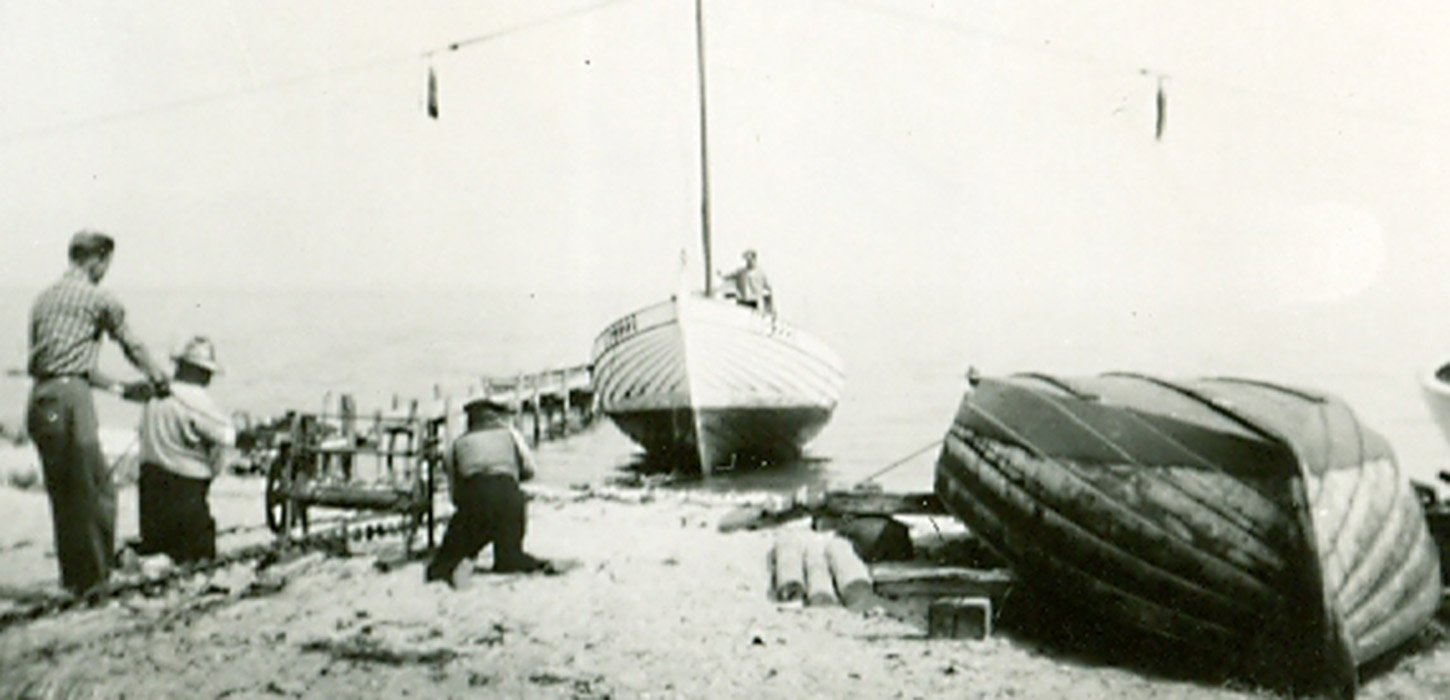 Poul Clausen er ved at få sin store fiskerbåd trukket op på stranden ved Maemosen.