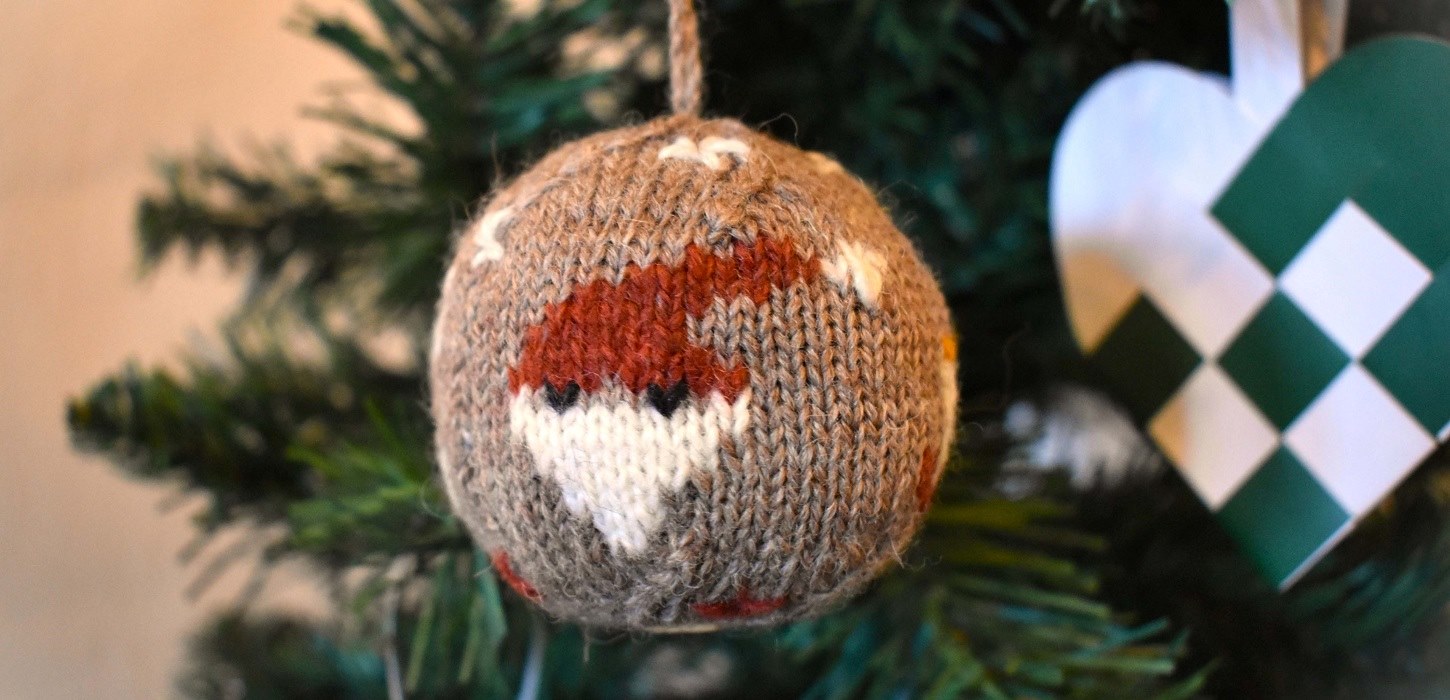 Die Weihnachtskugel 2024 ist aus Bio-Garn gestrickt und mit vier Weihnachtsmotiven versehen